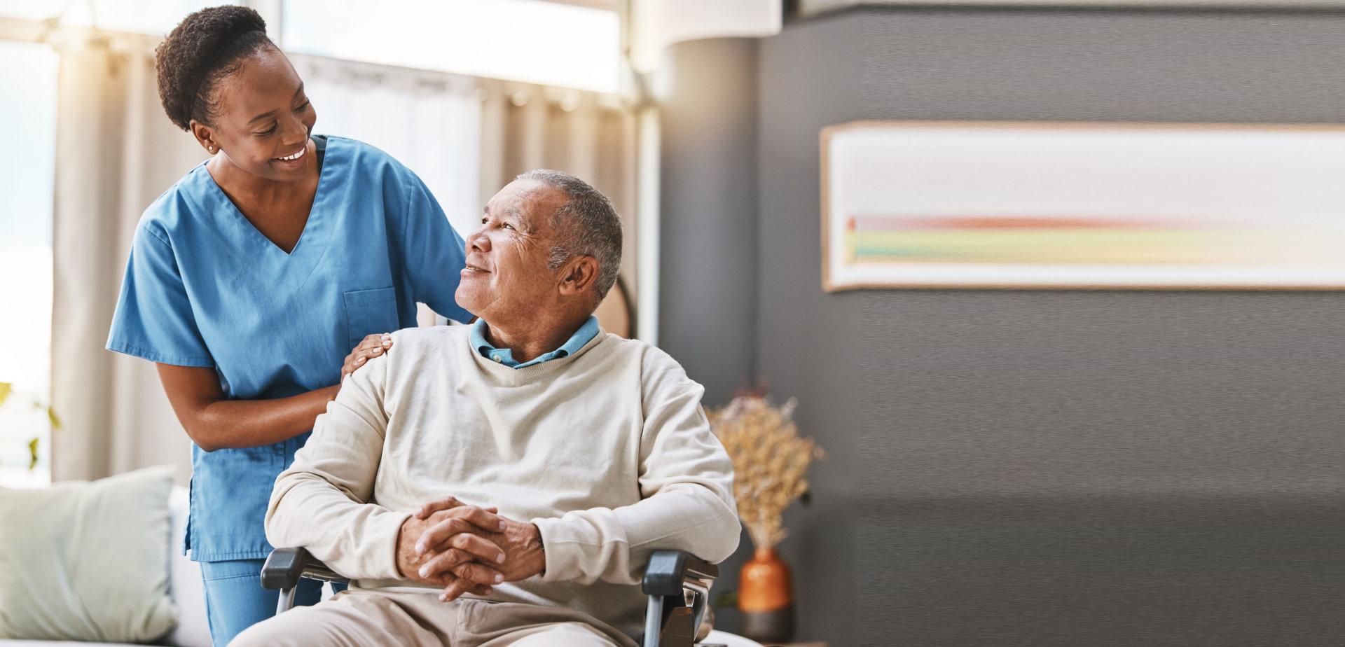 senior man on wheelchair smiling with his professional caregiver